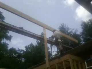 Carpenter setting a ridge beam over a new addition frame — Ice Dam Removal by Roofing Brothers in Hastings On Hudson