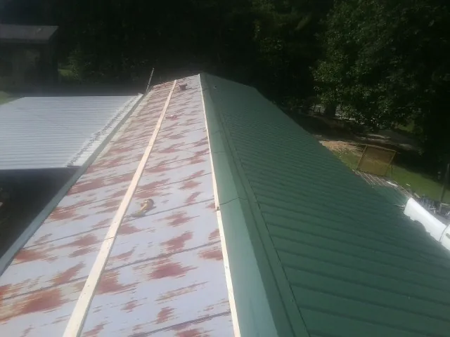 Old rusted panels beside newly installed green metal roofing — Wind Damage Roof Repair by Roofing Brothers in Hastings On Hudson