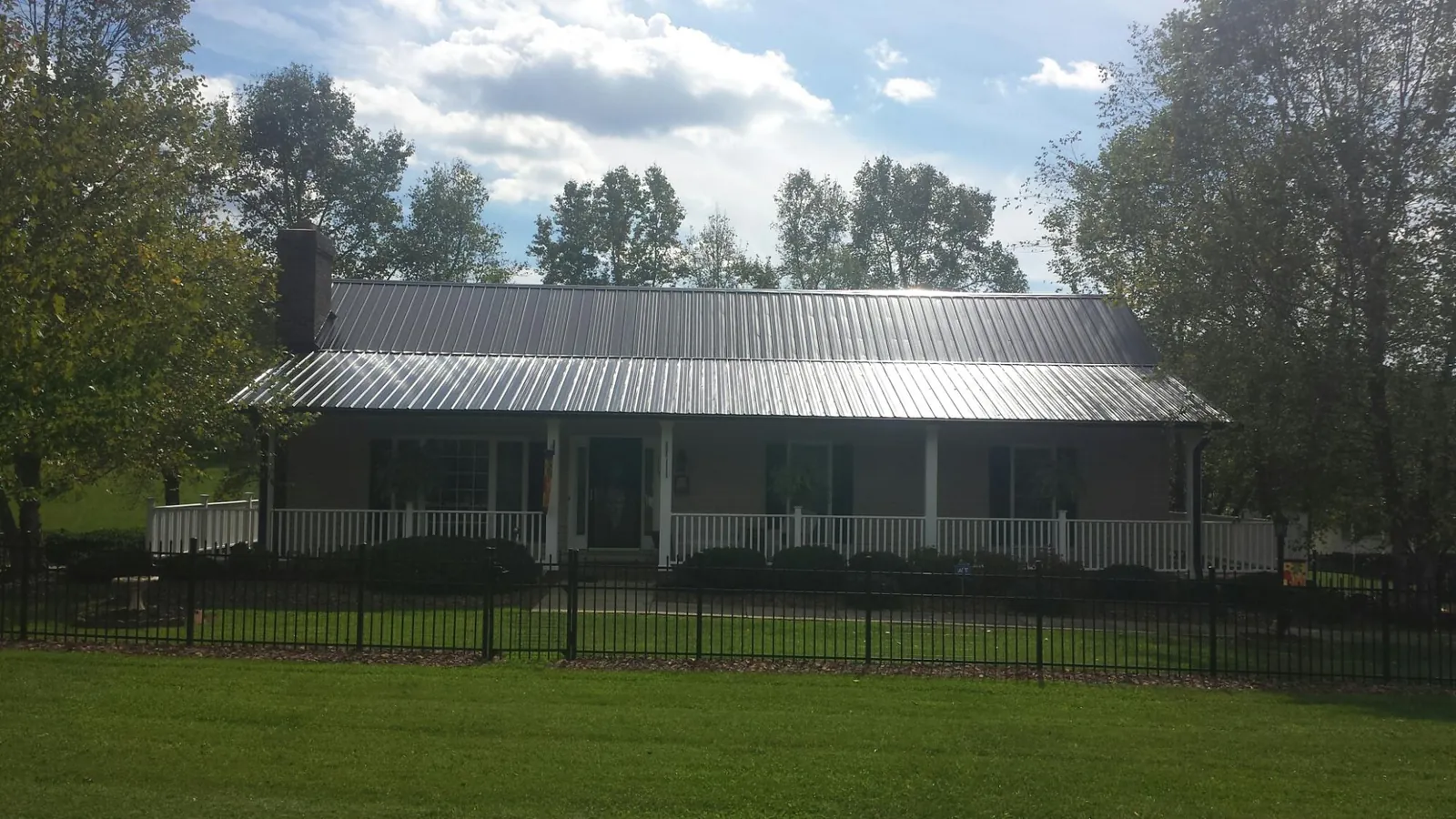 Gray metal roof on a brick ranch with a full width front porch — Gutter Guard Installation work by our crew in Hastings On Hudson
