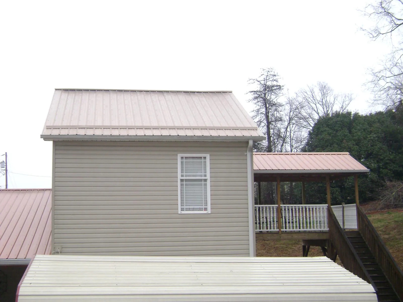 Tan metal roofs on a two story addition and attached porch, from a Roof Replacement job in Hastings On Hudson