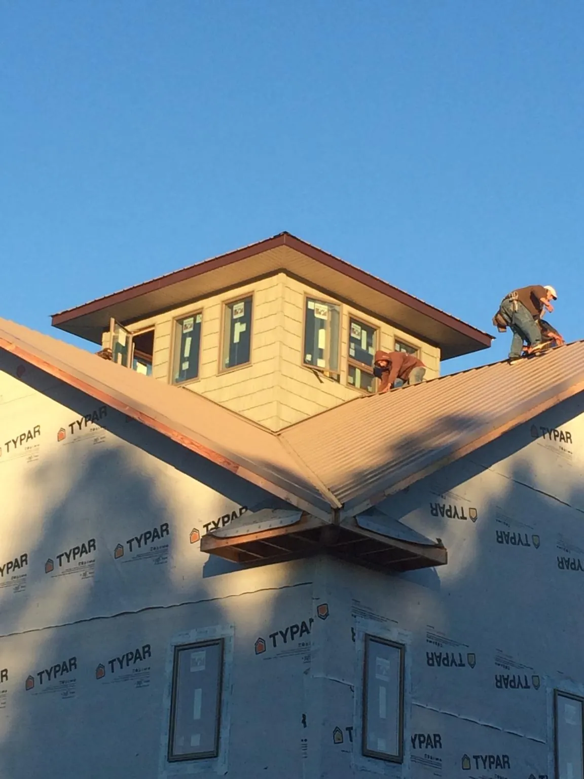 Roofers working around a rooftop cupola on a new metal roof at sunset — Roof Waterproofing in Hastings On Hudson by Roofing Brothers